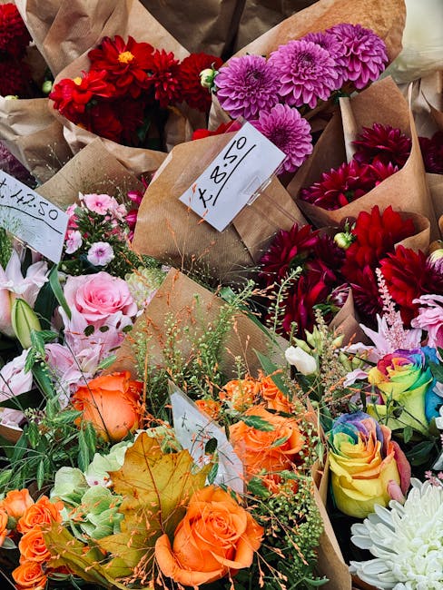 A vibrant collection of freshly arranged flower bouquets displayed together, featuring a variety of colorful blooms including red dahlias, purple chrysanthemums, pink roses, orange spray roses, and mu