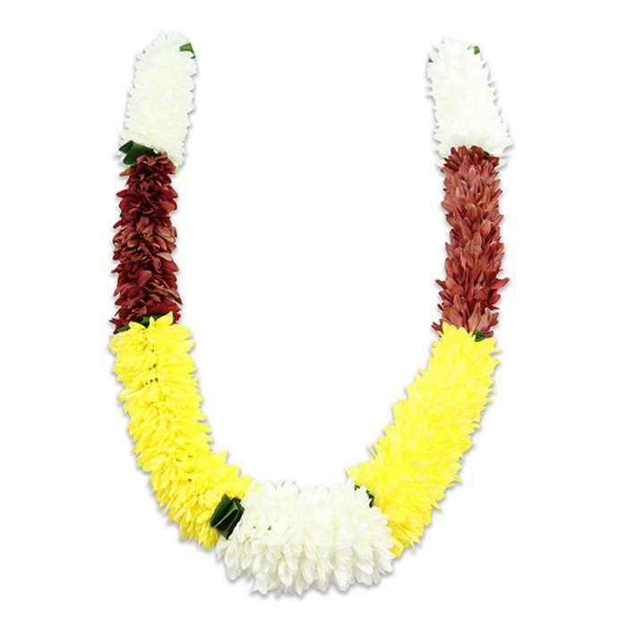 Set against a pristine white background, this U-shaped decorative garland reveals meticulous artisan technique in its bold, banded colouring and plush, fabric-petal texture. Each arm begins with a compact cylinder of pure white blossoms - small, chrysanthemum-like artificial flowers whose multitude of tiny fabric petals form a feathery, voluminous surface. Immediately beneath these, a rich maroon segment provides a concentrated, earthy counterpoint; the maroon petals are tightly grouped, offering a textured density that visually grounds the piece. The dominant field that follows is a long, cheerful band of sun-bright yellow, crafted from numerous small synthetic petals arranged to resemble marigolds or miniature dahlias; this yellow section creates the broad, sweeping curve of the U and supplies visual warmth and buoyancy. At the garland's lowest point, where the two yellow arms meet, a substantial cluster of white blooms-similar to the top sections-forms a central focal knot, while small dark green leaf accents appear at key junctions to separate colours and lend a subtle botanical rhythm. The materials read as fabric and faux foliage, selected for durability so the garland will endure multiple ceremonies or display settings; careful layering and dense stitching give it a uniformly full silhouette and a soft, tactile presence despite its synthetic makeup. In Cobham, from ceremonies in private home shrines to community festival offerings, this mala carries cultural meaning - white for purity, yellow for prosperity, maroon for devotion - and suits occasions such as Hindu pooja, weddings, temple adornments, Diwali and Holi. As a local florist who often prepares ceremonial pieces near Cobham High Street and the lanes toward Painshill, I describe this garland as formal, comforting, and built to honour ritual with quiet dignity.