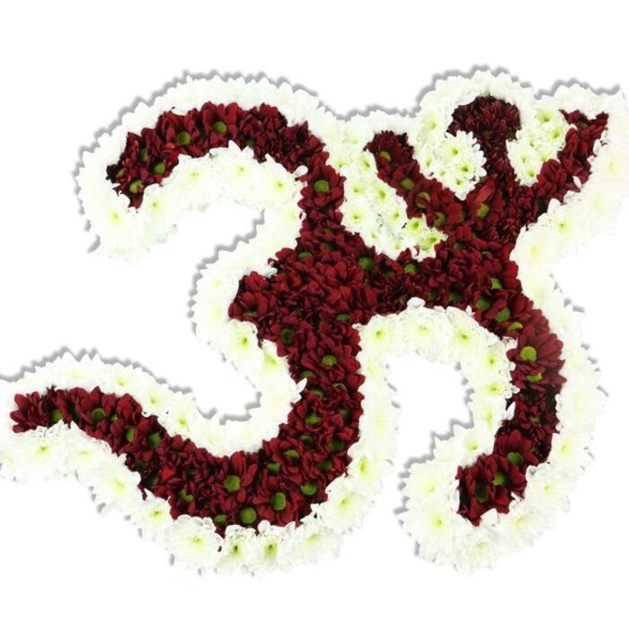 A reverent, hand-built floral Om (Aum) motif sits against a pure white field, its form articulated by thousands of tiny, deep maroon and burgundy chrysanthemum-like blooms, each with a pale lime-green centre that picks out the texture of the massed petals. The symbol's looping ʻ3ʼ-form, the downward S-shaped stroke and the crescent with dot are all modelled in rich, velvety red florals, while a generous, undulating rim of spotless white spray chrysanthemums traces the outer edges and interior negative spaces, producing a crisp, high-contrast silhouette. The density of the flowers lends the composition a plush, tactile quality; petals overlap like layered textiles and reflect the soft studio light, which creates a faint shadow beneath the piece and gives a subtle sense of elevation. There is a quietly grounding aroma-gentle, slightly sweet and herbaceous-that suits moments of reflection and ceremonial quiet. The arrangement reads as devotional sculpture: careful, patient construction that would command respect in a memorial setting, find place on an altar at a cultural celebration, or act as a contemplative focal point in a yoga or meditation gathering in local community spaces near Painshill Park or along Cobham's quieter lanes. As a local florist's creation, it suggests familiarity with Surrey tastes for understated elegance and reverence. The overall impression is one of calm dignity and tactile beauty; a crafted tribute that brings colour, texture and spiritual meaning together in service to remembrance and ritual.